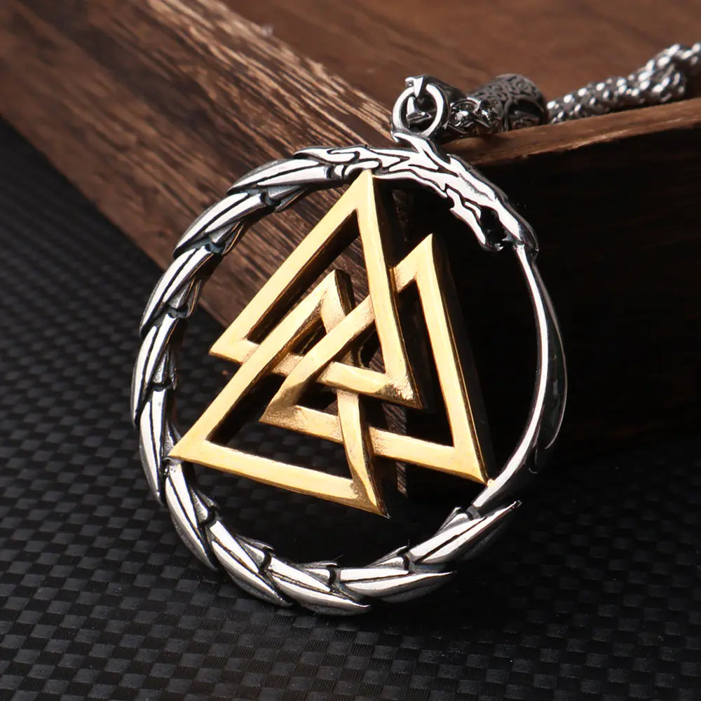 Gold and silver Valknut pendant on a textured surface