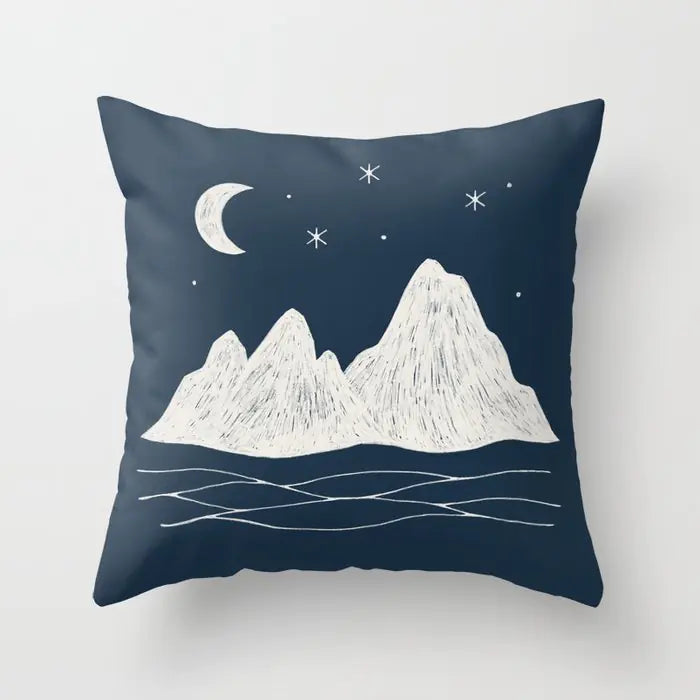 Navy blue pillow with white mountain and celestial design on a light gray background