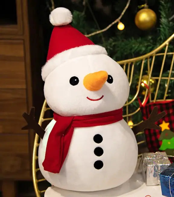 Snowman decoration with a red hat and scarf, standing in front of a Christmas tree and presents.