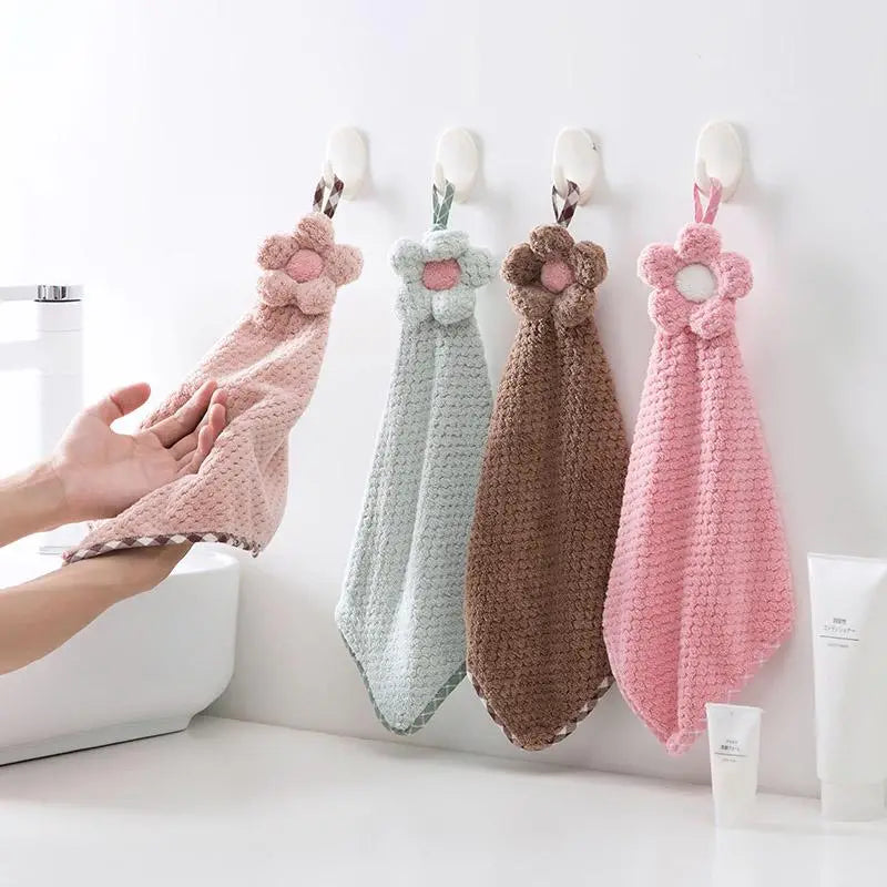Four crocheted hand towels with floral ends hanging on hooks against a white background.