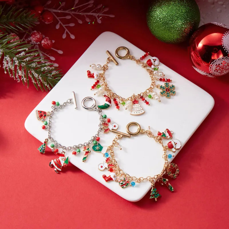 Three Christmas-themed gold bracelets on a white plate with festive decorations in the background.