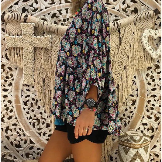 Person wearing a colorful floral dress with intricate patterns against a decorative stone wall.