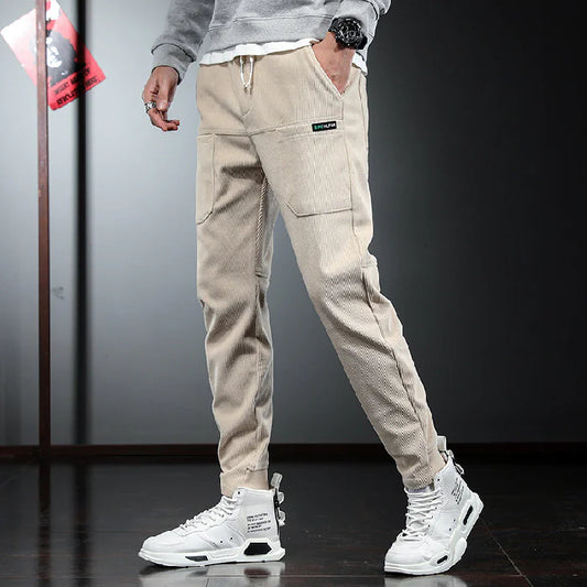 Person wearing beige cargo pants and white sneakers on a dark floor.