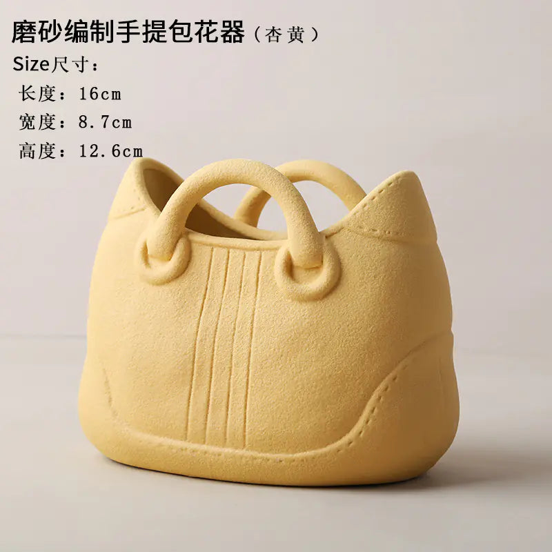 Yellow handbag-shaped flower pot with text on a light gray background