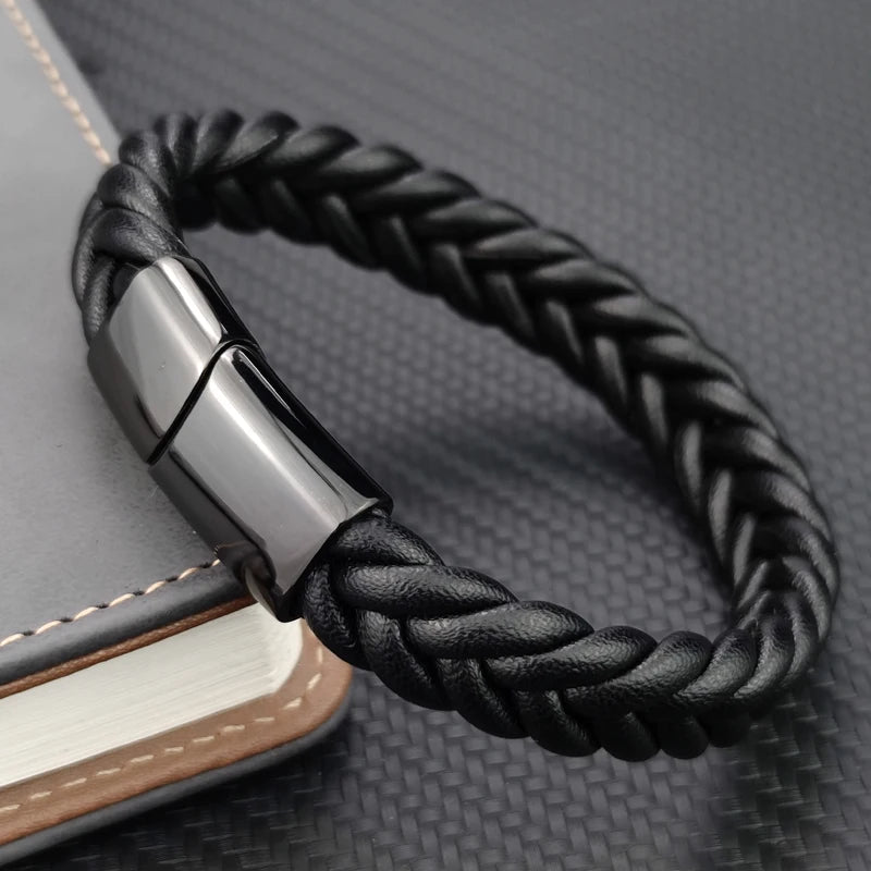 Black braided leather bracelet with silver clasp on a textured surface