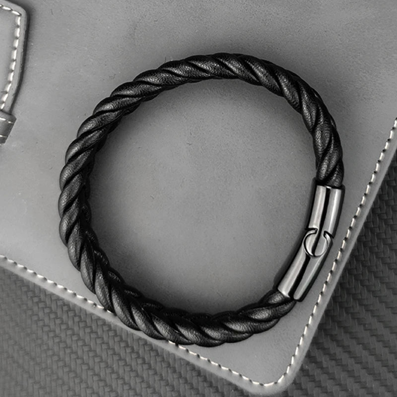 Black braided leather bracelet with silver clasp on a gray textured background