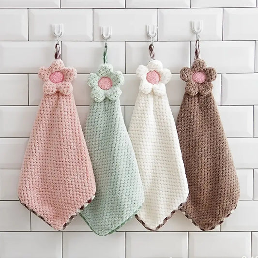 Four crocheted hanging towels with floral designs on a tiled wall.
