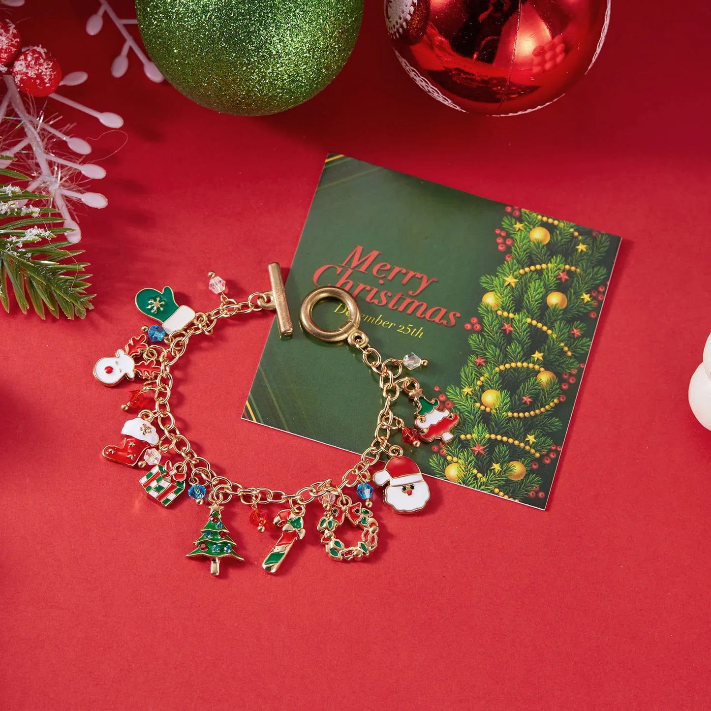 Gold charm bracelet with festive charms on a red background with Christmas decorations.