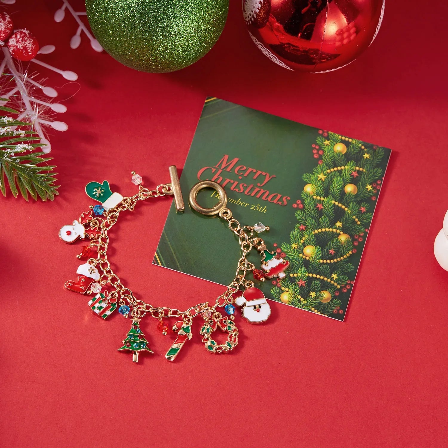 Gold charm bracelet with festive charms on a red background with Christmas decorations.