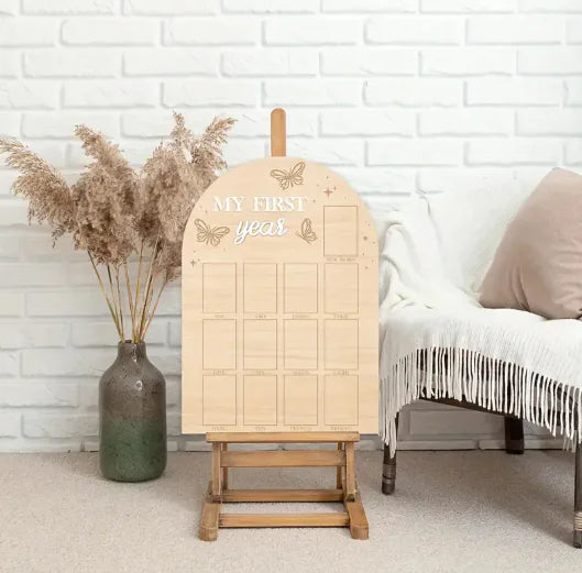 Wooden photo album with 'My First Year' text on a stand against a white brick wall.