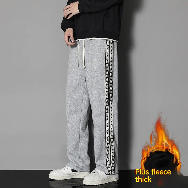 Unisex straight-leg casual exercise pants in black with drawstring waist, shown with side stripe detail and sneakers