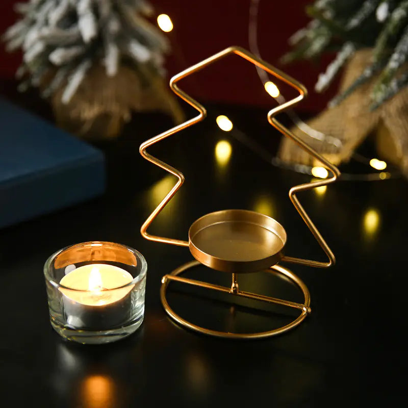 Gold Christmas tree-shaped candle holder with a lit candle on a dark surface.