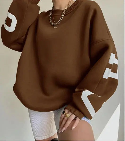Brown sweatshirt with white lettering worn by a person against a neutral background