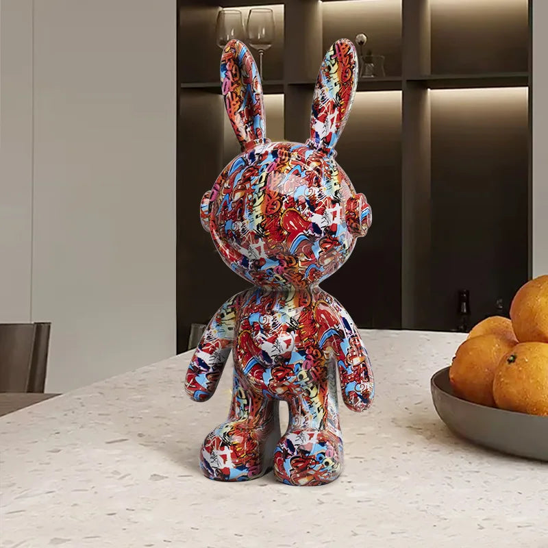 Colorful rabbit sculpture on a table with a bowl of oranges in the background