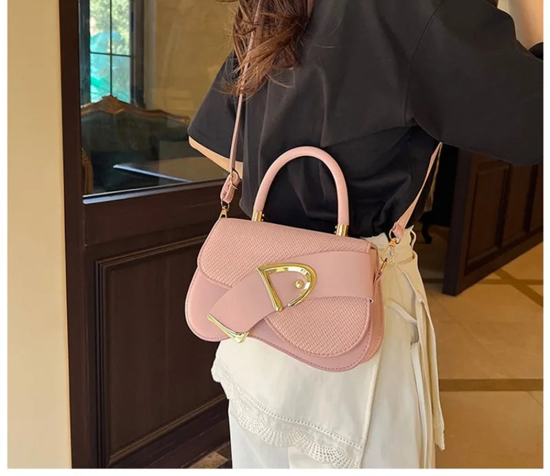 Person holding a pink handbag with gold accents indoors