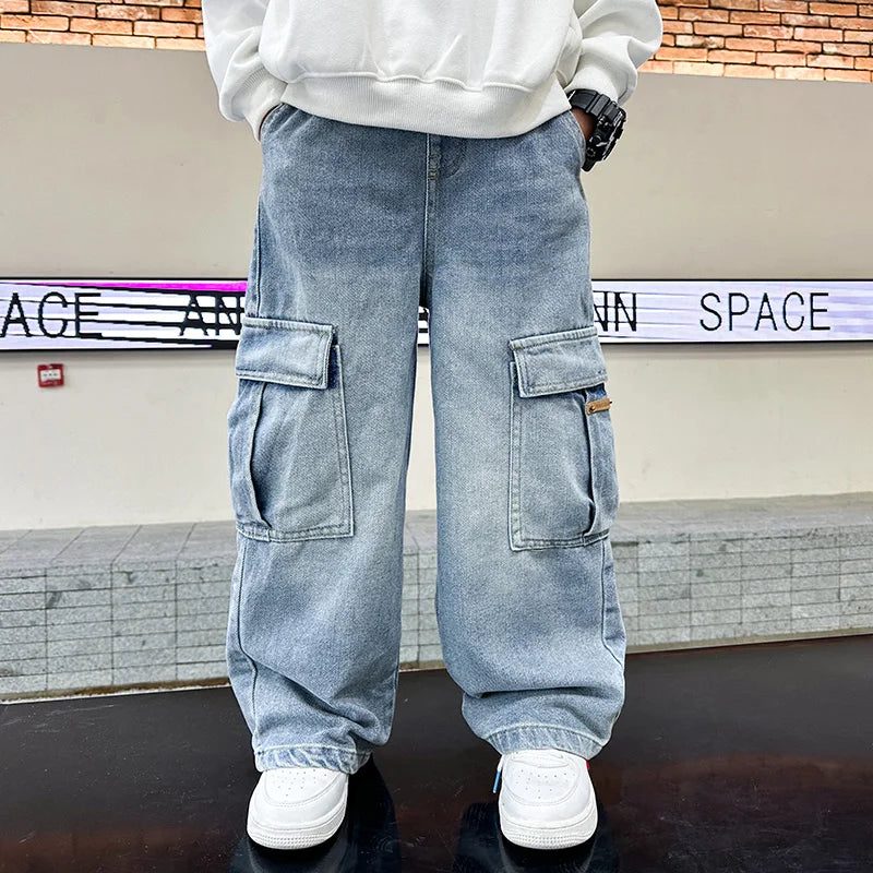 Person wearing light blue cargo pants with a white sweatshirt and white sneakers in front of a wall with text.