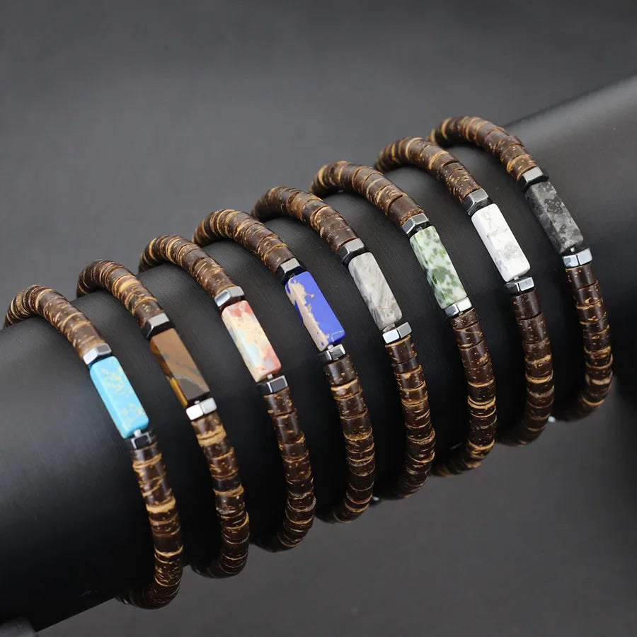 Set of wooden beaded bracelets with colored stone accents on a dark surface