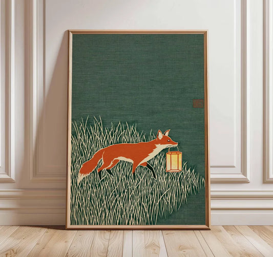 Minimalist Japanese-inspired fox art print showing an orange fox carrying a lantern through tall grass against a deep green background in a natural wood frame.