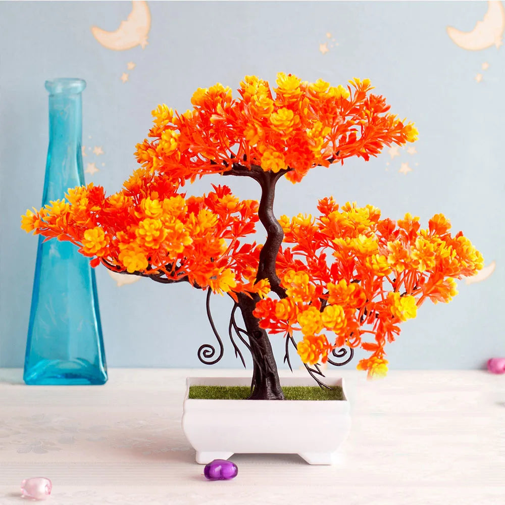 Artificial orange and yellow bonsai tree in a pot with a blue vase in the background.