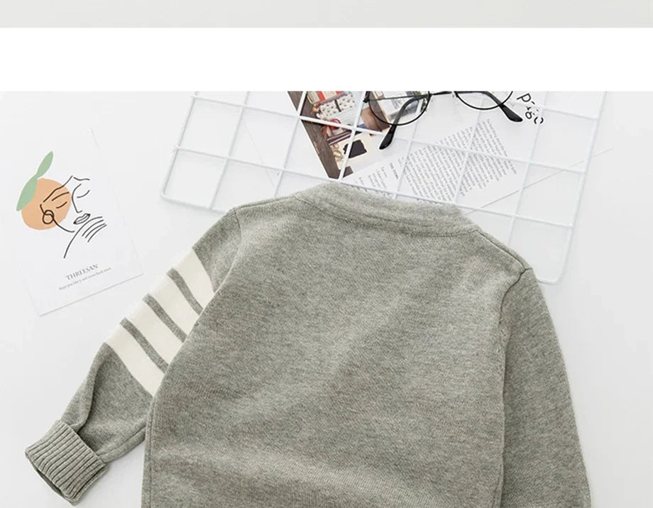 Grey sweater with striped sleeves on a white surface