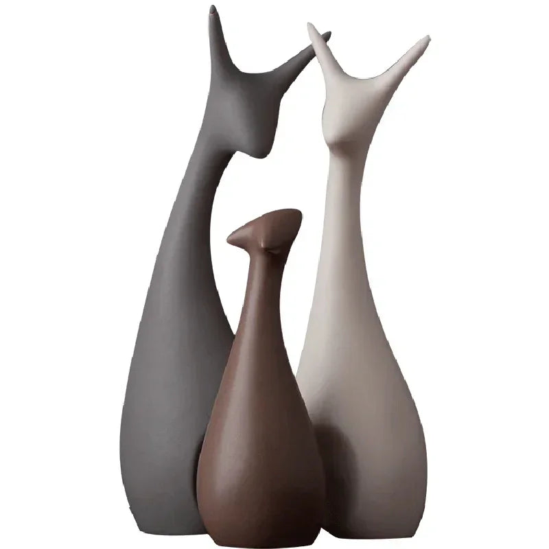 Three ceramic deer figurines in gray, brown, and beige on a white background