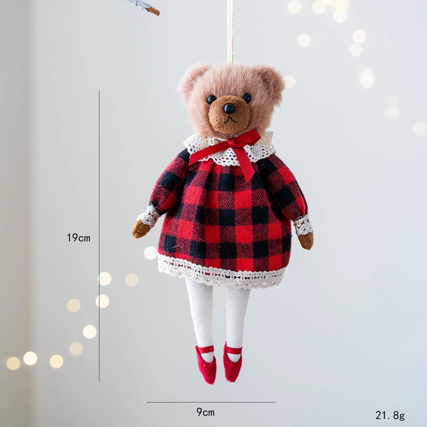 Teddy bear in a red and black checkered dress with measurements on a light gray background