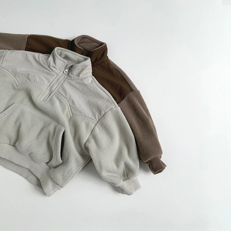 Two fleece jackets, one gray and one brown, on a white background