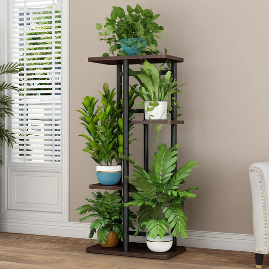 Tall plant stand with multiple potted plants against a beige wall.