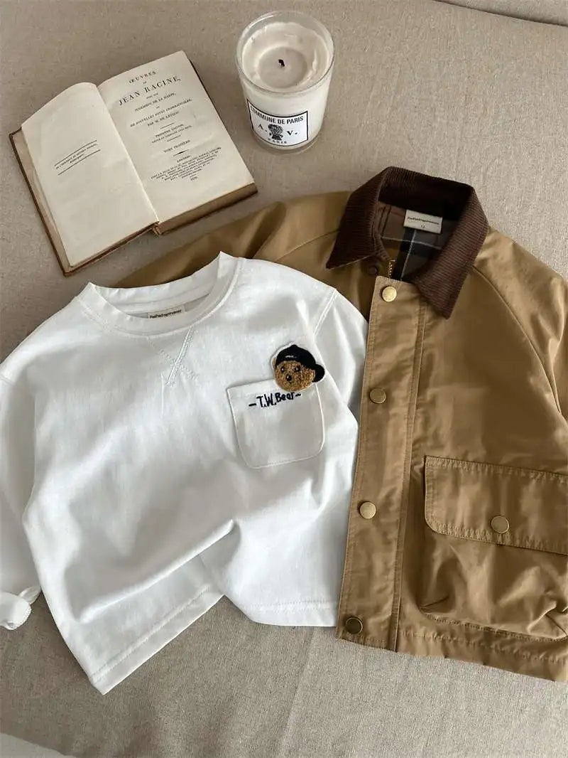 White t-shirt with a pocket design, brown jacket, and candle on a textured surface