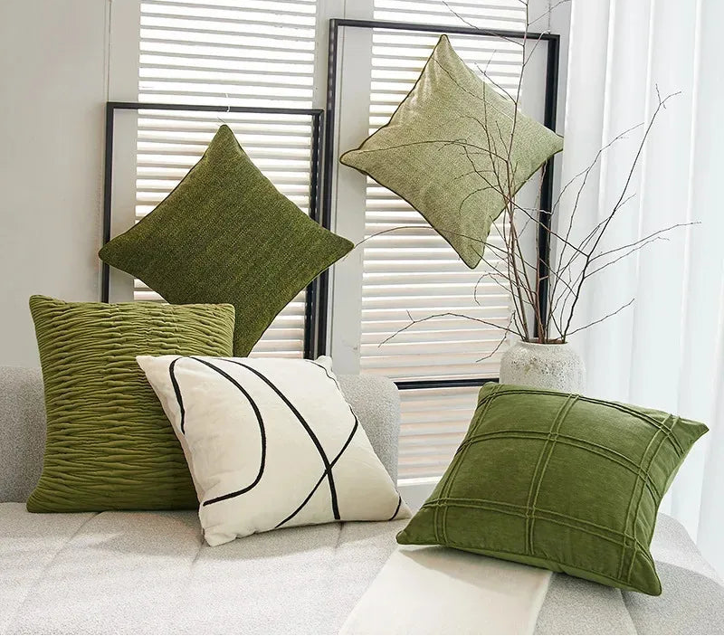 Green and white pillows on a sofa with a neutral background