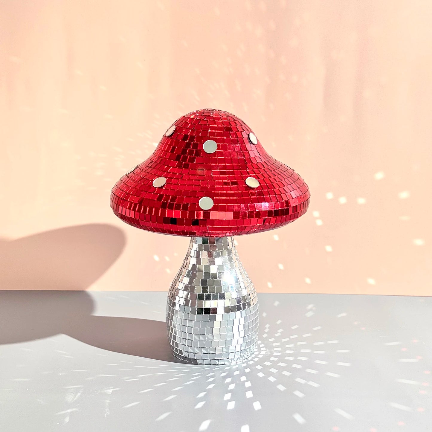 Mushroom-shaped ornament with red top and silver base on a light background