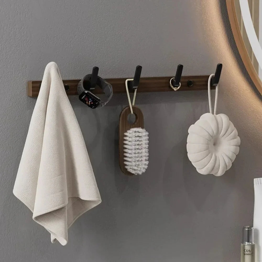 Wall-mounted hooks with a towel, brush, and scrubber against a gray wall.