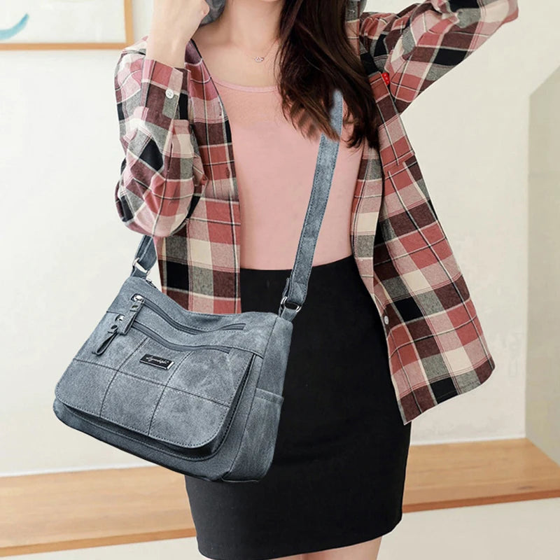 Person wearing a plaid shirt and carrying a gray handbag indoors.