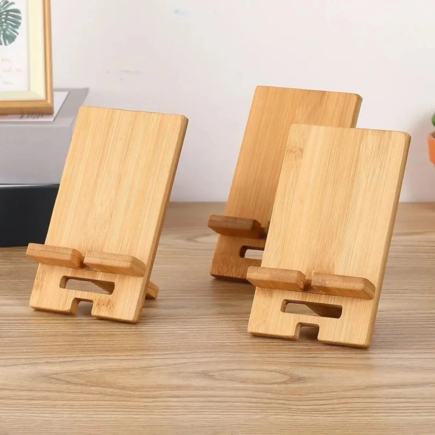 Three wooden phone stands on a wooden surface with a neutral background