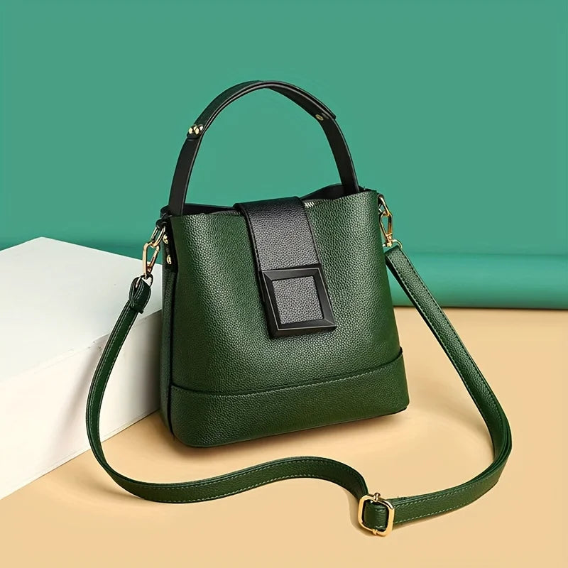 Green handbag with a black strap on a beige surface against a teal background