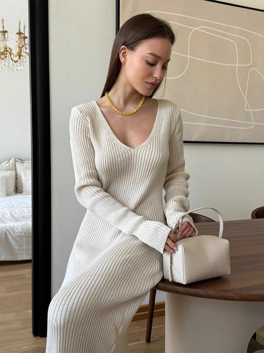 Woman wearing a cream ribbed knitted maxi dress with V-neck and long sleeves, Blubelle fashion.
