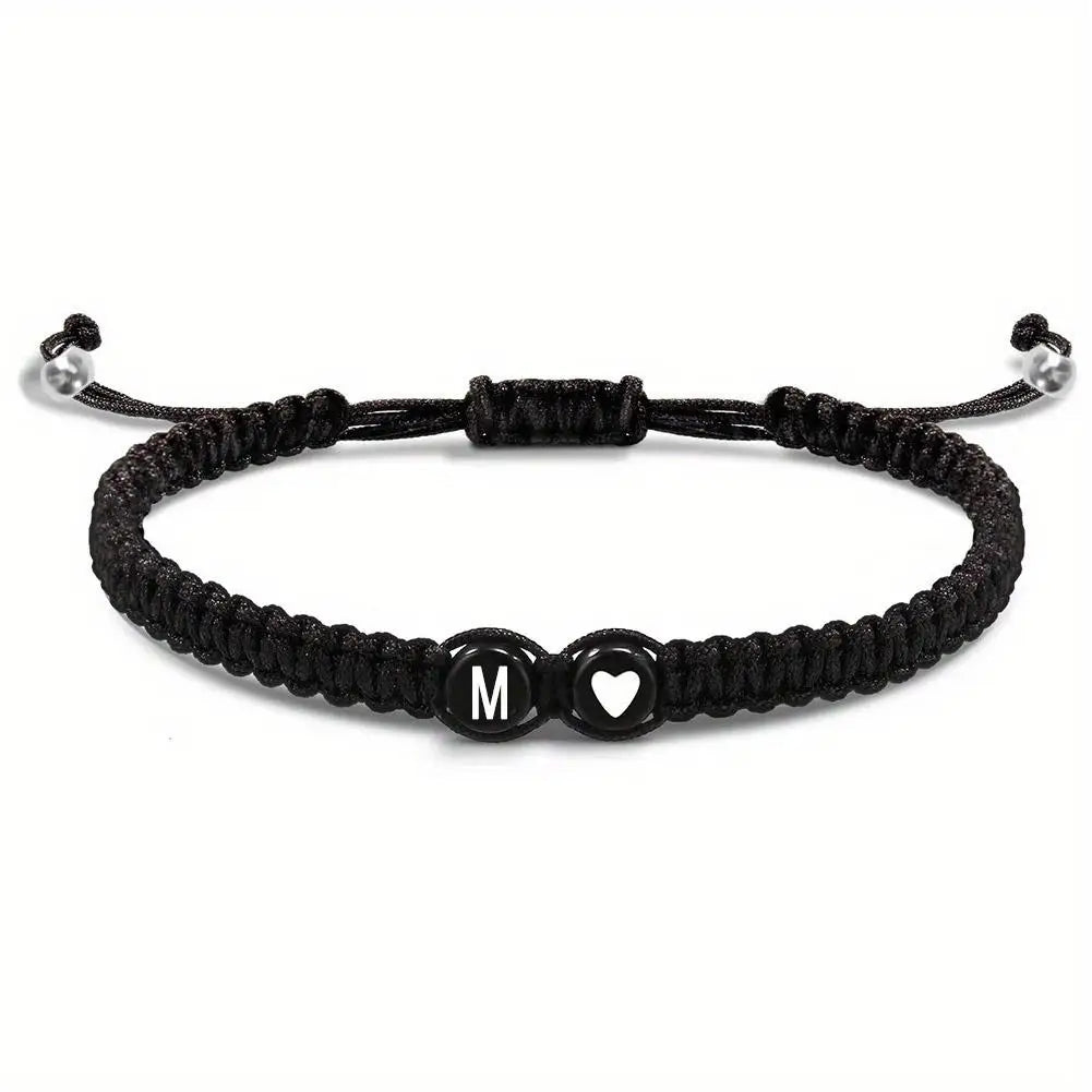 Black braided bracelet with letter 'M' and heart charm on a white background