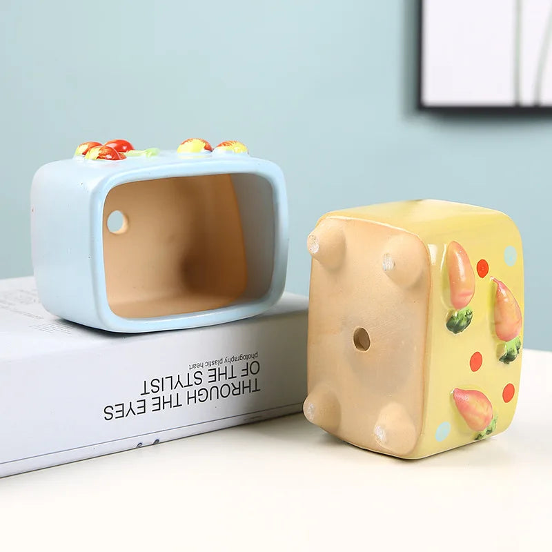 Two cartoonish ceramic cubes on a surface with a light blue background