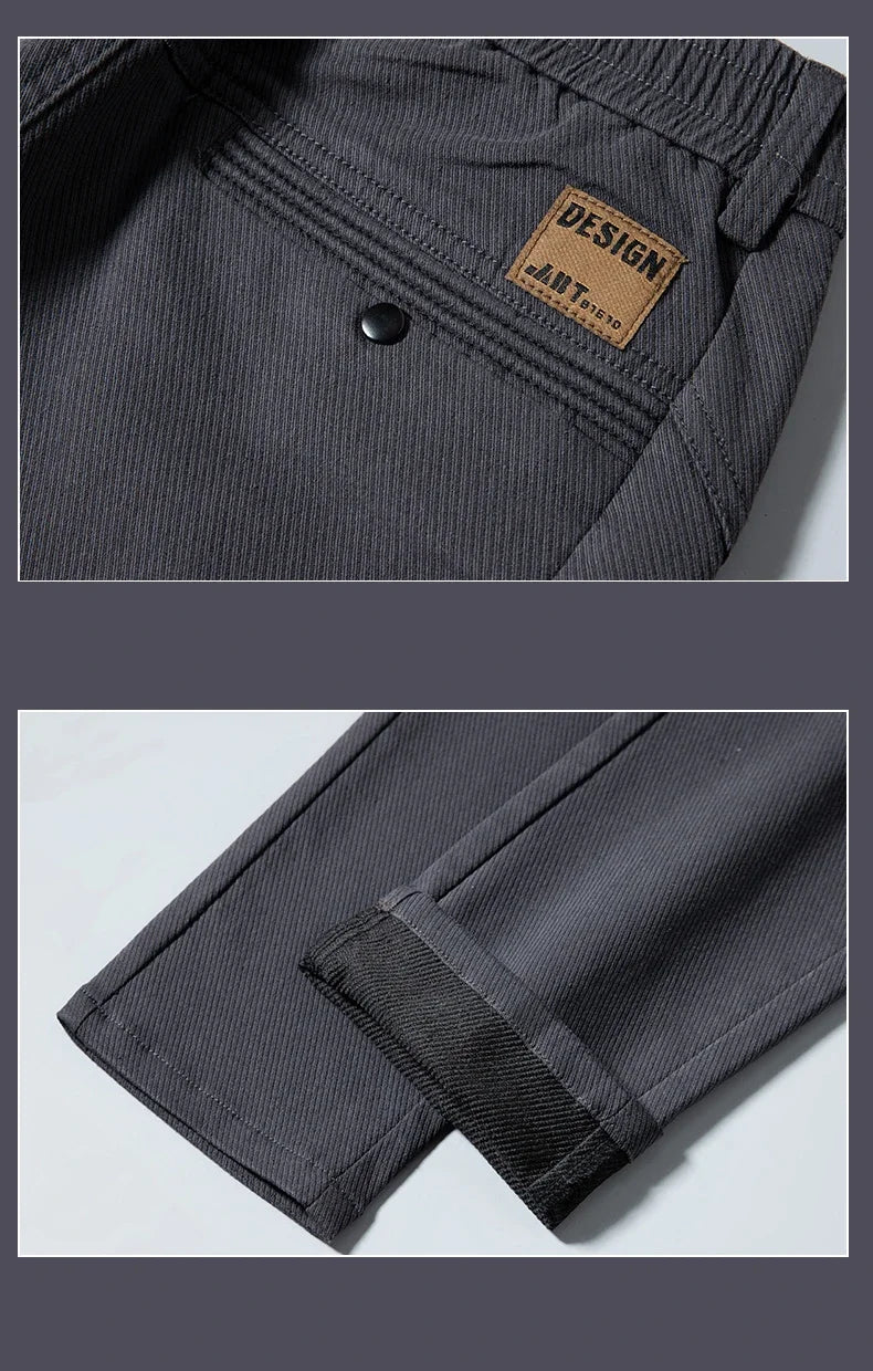 Close-up of dark gray pants with a brand label and button, on a light gray background.