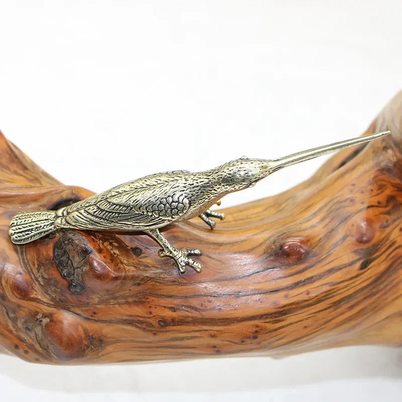 Bronze bird figurine on a wooden log with a white background