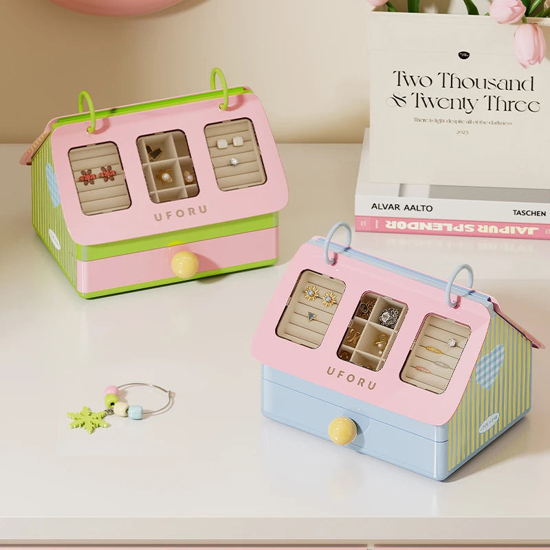 Pastel house shaped jewellery organiser box with clear display windows for rings and earrings on a dressing table