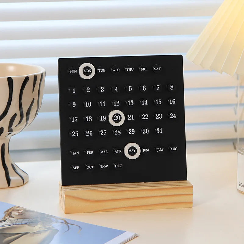 Black calendar with wooden stand on a surface with a blurred background