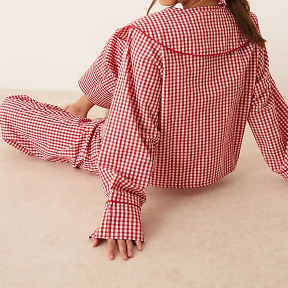 Person wearing a red and white checkered outfit sitting on a beige surface