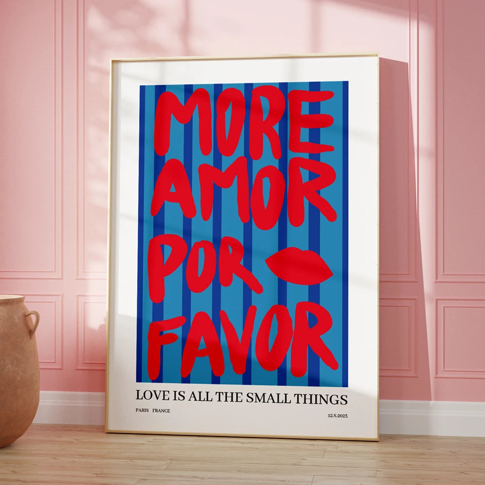 Framed poster with 'More Amor Por Favor' text on a blue background, leaning against a pink wall.