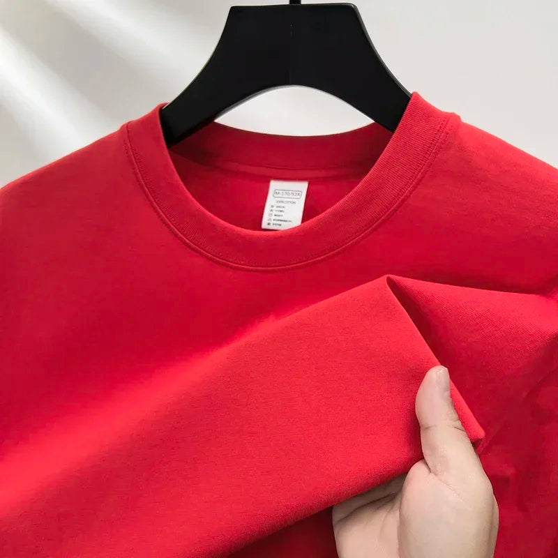 Red sweatshirt on a hanger with a hand adjusting it against a neutral background