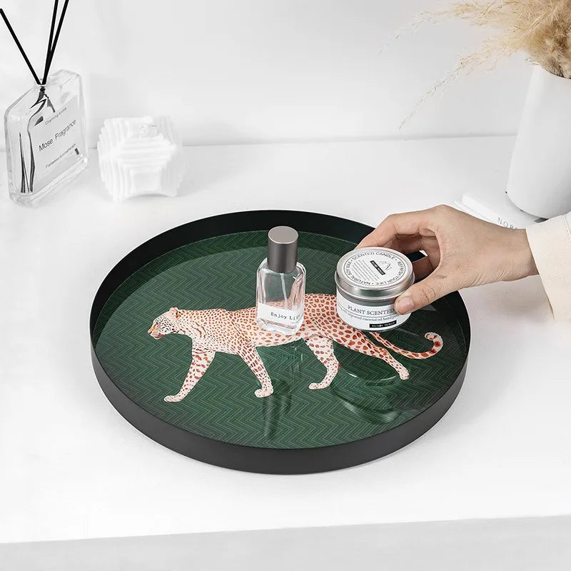 Round decorative tray with a leopard design on a white surface, holding a bottle and a jar.
