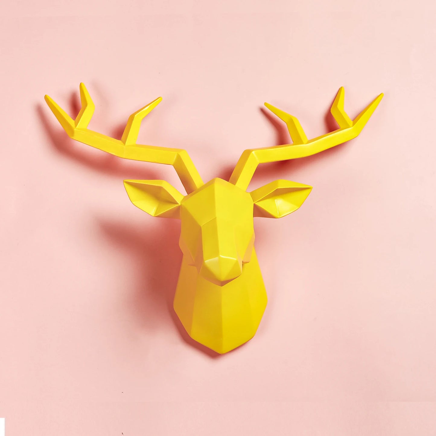 Yellow deer head wall decoration on a pink background