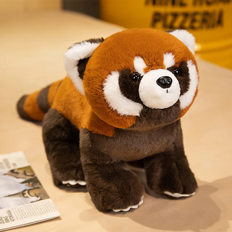 Plush toy red panda on a beige surface with a yellow box in the background