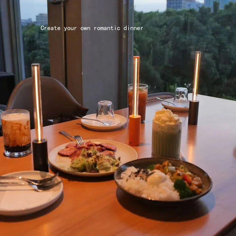 Dinner table set with plates of food, drinks, and candles with a scenic view in the background.