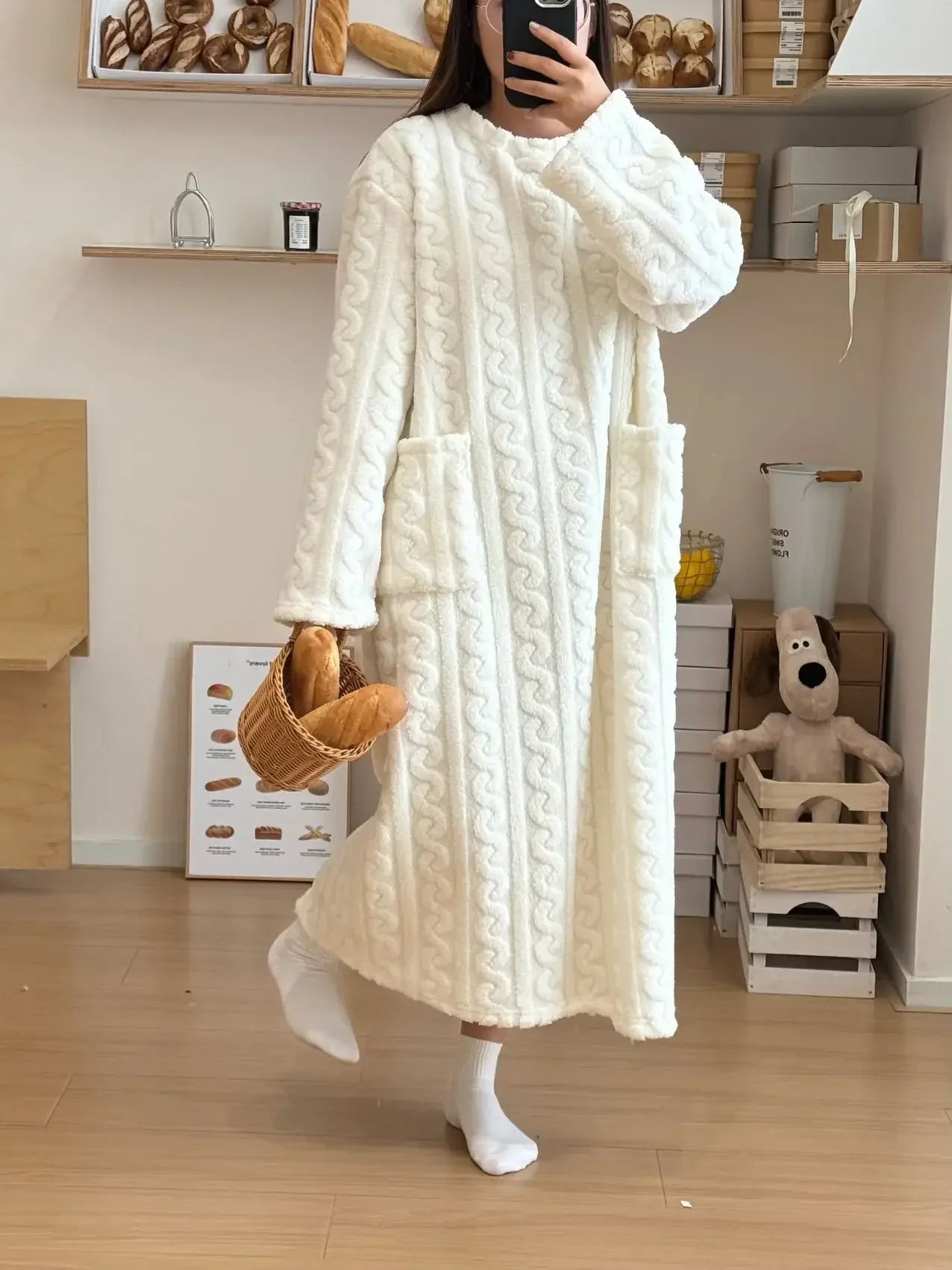 Person wearing a long, textured white robe in a room with wooden shelves and toys.